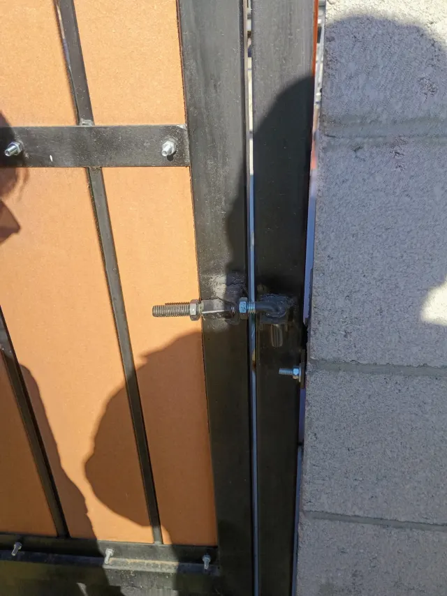 Gate hinge and latch hardware against a block wall